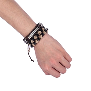 Detailed view of multilayer woven bracelet with engraved 'Where there's a will' metal plate
