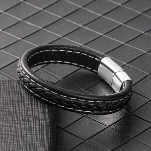 Gros plan d'un bracelet en cuir tressé noir avec un fermoir magnétique en métal poli