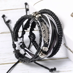 Vintage multi-layer braided leather bracelet set with feather charm on wooden background