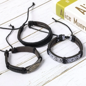 Three-piece set of ethnic braided leather bracelets featuring a vintage metal feather pendant