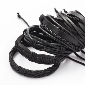 Macro view of multi-layer black braided leather and fiber bracelets with adjustable knots