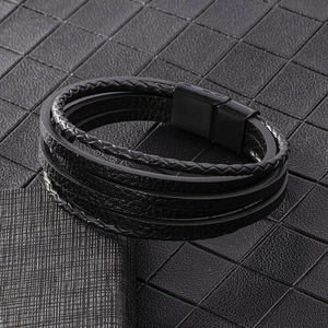 Detailed macro view of multi-layer woven black leather bracelet with magnetic metal clasp