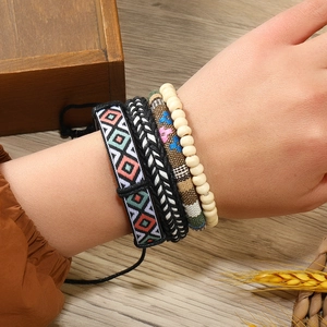 Détail de bracelets bohèmes superposés avec motifs tissés et perles en bois au poignet