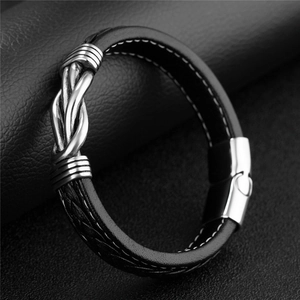 Macro shot of black woven leather men's bracelet with twisted silver metal knot detail