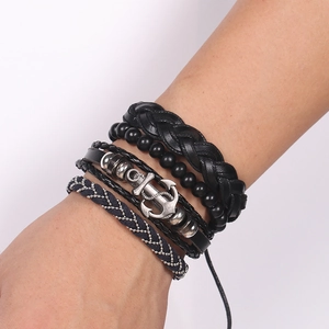 Close-up of men's nautical leather bracelets featuring silver anchor charm and woven cords