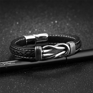 Men's black braided leather bracelet featuring a silver infinity knot and magnetic clasp