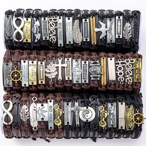 Detail of multilayer woven leather bracelets with charms like cross, feather and anchors