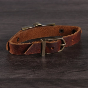 Vintage brown leather yin yang bracelet set with brass buckle on wood background