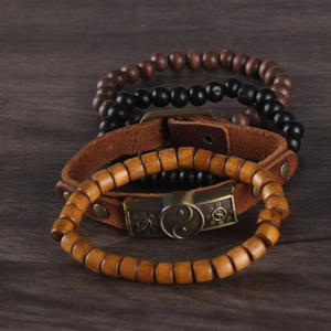 Macro detail of men's leather and wood bead bracelet with bronze Yin Yang charm
