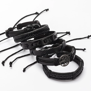 Detail of multi-layer black leather bracelets with woven straps and Tree of Life pendant
