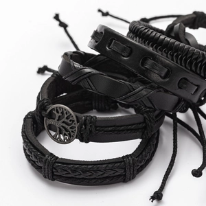 Detailed view of layered black leather bracelets with Tree of Life metal charm and braids