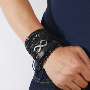 Detail of men's layered black woven leather bracelets with silver infinity charm
