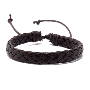 Detail van donkerbruine gevlochten leren armband met verstelbare trekkoordsluiting en textuur