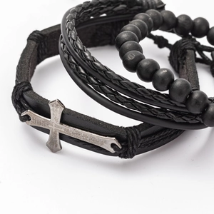 Detail shot of multi-layer black leather wristband with engraved metal cross and matte beads