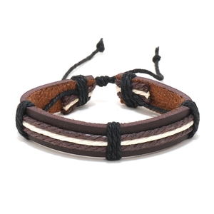 Détail du bracelet en cuir marron multicouche avec textures de cordes tressées noir et blanc
