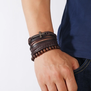 Detail of men's layered leather bracelet featuring wooden beads and a metal cross pendant