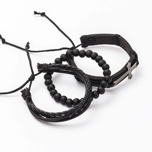 Detailed view of three-piece men's black leather and matte bead bracelets with silver cross
