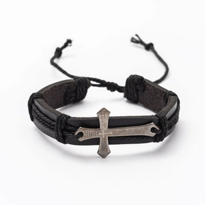 Macro detail of men's leather bracelet with engraved cross and braided black cords