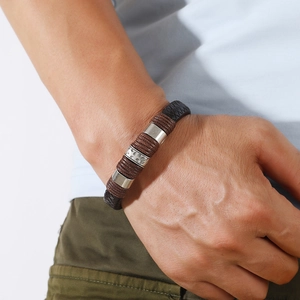 Detail eines dunkelbraunen Lederarmbandes mit silbernen Metallverzierungen am Handgelenk