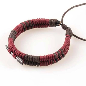 Macro detail of hand-woven cord bracelet with a vintage metal arrow charm and adjustable knot