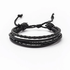 Detail of multi-layer black braided leather bracelet with adjustable drawstrings on white background