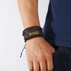 Detail view of men's layered leather bracelet featuring a bronze cross plaque and wooden beads