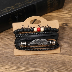 Détail du lot de quatre bracelets en cuir noir et perles de bois avec breloque plume sur carton