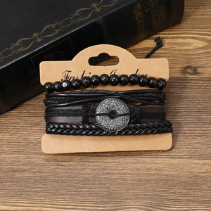 Detail of vintage multilayer leather bracelets with antique silver charms on wood