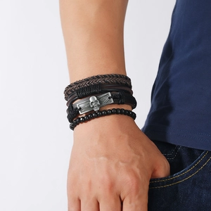 Detail of vintage multilayer men's leather bracelet with silver skull charm and black beads