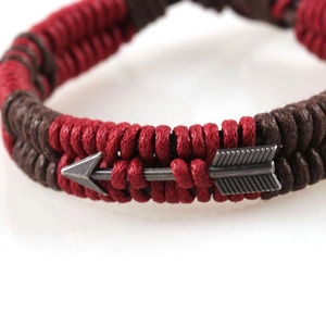 Arrow metal charm bracelet with red and brown woven cord in a minimalist style
