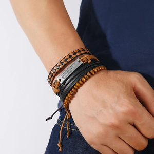 Macro shot of men's layered leather bracelets with engraved metal plaque and wood beads