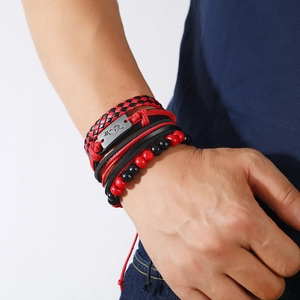 Close-up of multilayer leather bracelets set with metal plate and red beads on man wrist