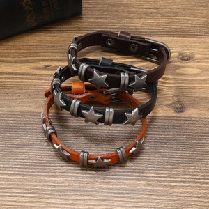 Three punk star rivet leather bracelets in black, brown and orange colors on wood table
