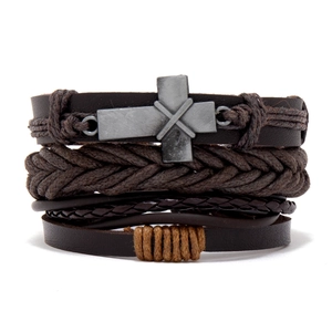 Detail of vintage multilayer braided leather bracelet with an antique metal cross charm