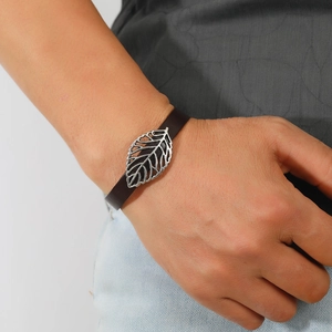 Retro brown leather bracelet with silver leaf metal charm worn on a model wrist