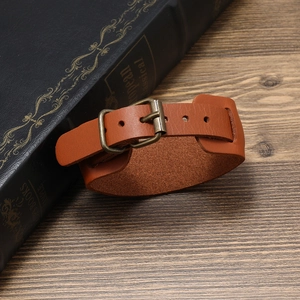 Retro wide leather bracelet for men with vintage bronze buckle on dark wooden surface