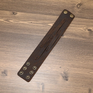 Vintage brown leather wide bracelet for men with retro punk buckles on wood surface