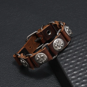 Detail of dark brown leather punk bracelet with silver fleur-de-lis studs and chain