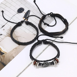 Detail of 3-piece black woven bracelet set featuring Tree of Life charm and wooden beads