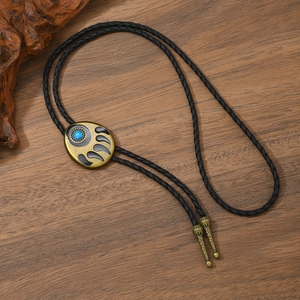 Close-up of vintage bronze bolo tie slide with blue turquoise and bear paw on wood surface