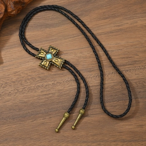 Detail of bronze cross bolo tie pendant with turquoise stone on braided leather cord