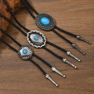 Three assorted western turquoise bolo ties with black braided leather cords on wood