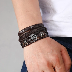 Close-up of multilayer leather bracelet with a metallic Tree of Life charm for men