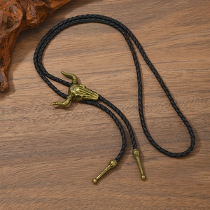 Close-up of western vintage bolo tie featuring detailed bull skull carving on dark wood
