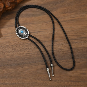 Vintage western bolo tie with turquoise stone and braided leather cord on wooden surface