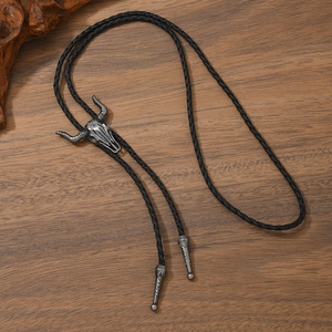 Detail of vintage silver bull skull bolo tie with floral engraving on braided leather cord