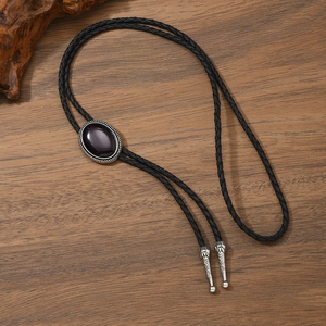 Detail of vintage bolo tie with black oval stone and silver engraved metal tips