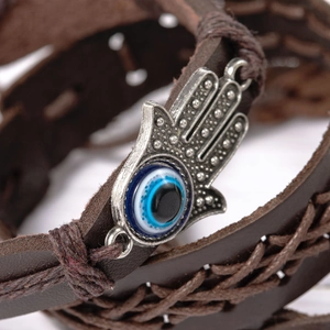 Makroaufnahme von Hamsa-Hand-Anhänger mit Evil Eye auf geflochtenem Lederarmband