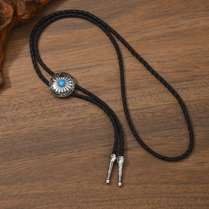 Detailed shot of a vintage turquoise bolo tie with silver metal buckle on a wood surface