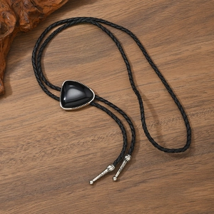 Western Bolo Tie mit schwarzem dreieckigem Edelstein und geflochtener Lederkordel auf Holz